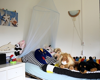 Ein Bett mit vielen Plüschtieren und einer Moskitonetz.