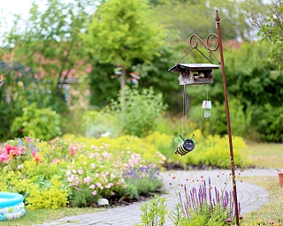 Ein blühender Garten mit einem Vogelhaus und bunten Blumen.