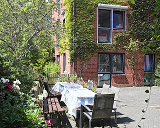 Ein einladender Garten mit Tisch und Stühlen, umgeben von Pflanzen.