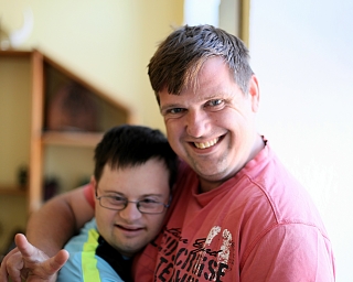 Ein Mann hält einen Jungen in den Armen und lächelt.