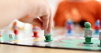 Ein Kind bewegt eine Spielfigur auf einem bunten Brettspiel.