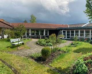 Panoramablick auf einen gepflegten Garten mit mehreren Gebäuden.
