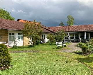 Ansicht von Gebäuden mit Garten und bewölktem Himmel.