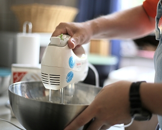 Eine Person benutzt einen Handmixer in einer Küche.