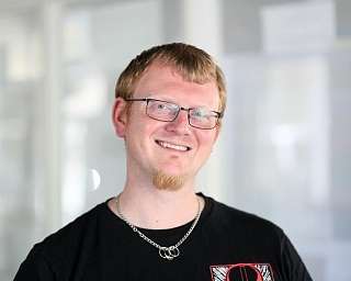 Ein Mann mit Brille und kurzem Haar lächelt freundlich.