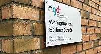 Hinweisschild für Wohngruppen an einer Backsteinwand.